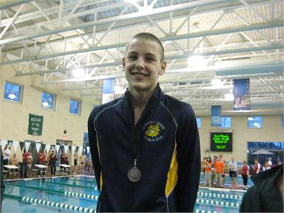 Junior Aidan Burton finished 2nd in the 100 backstroke at SWC and accepts his silver medal on the awards podium.